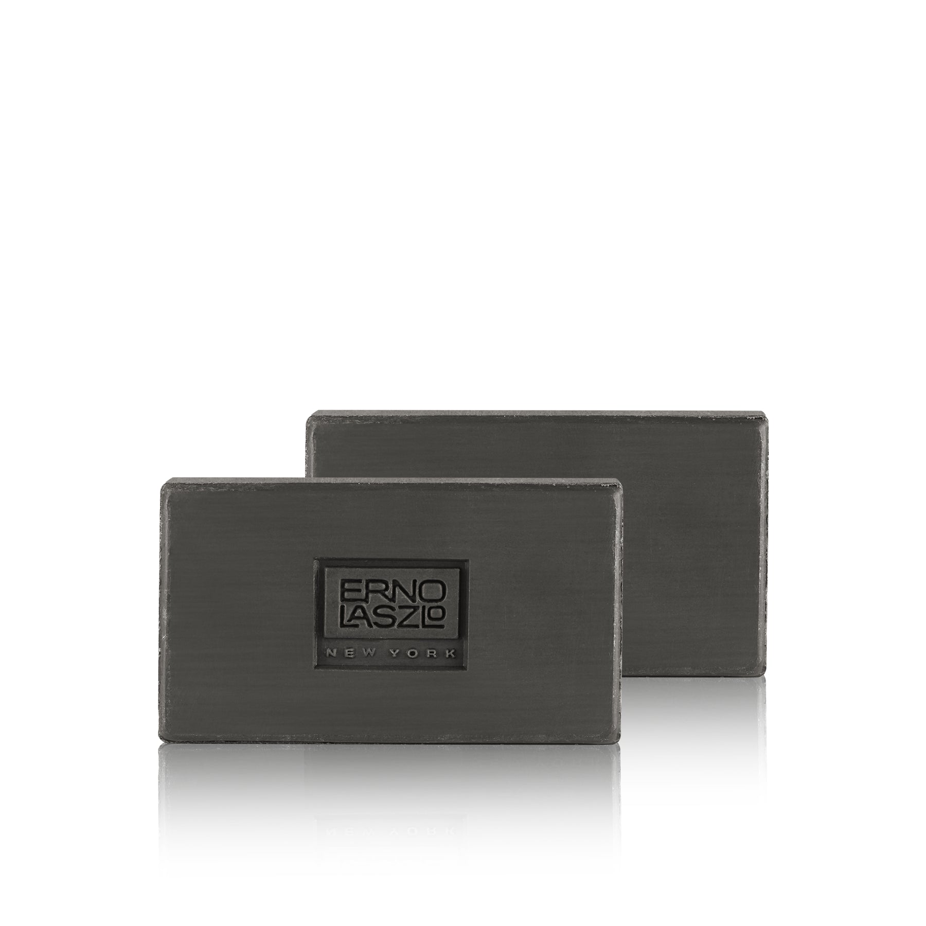 Two dark gray rectangular metal blocks with a brushed finish, featuring a central square logo plaque that reads 'ERNO LASZLO NEW YORK', shown on a clean white background with a soft reflection below.