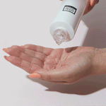 White squeeze skincare serum bottle dispensing clear gel onto open palm