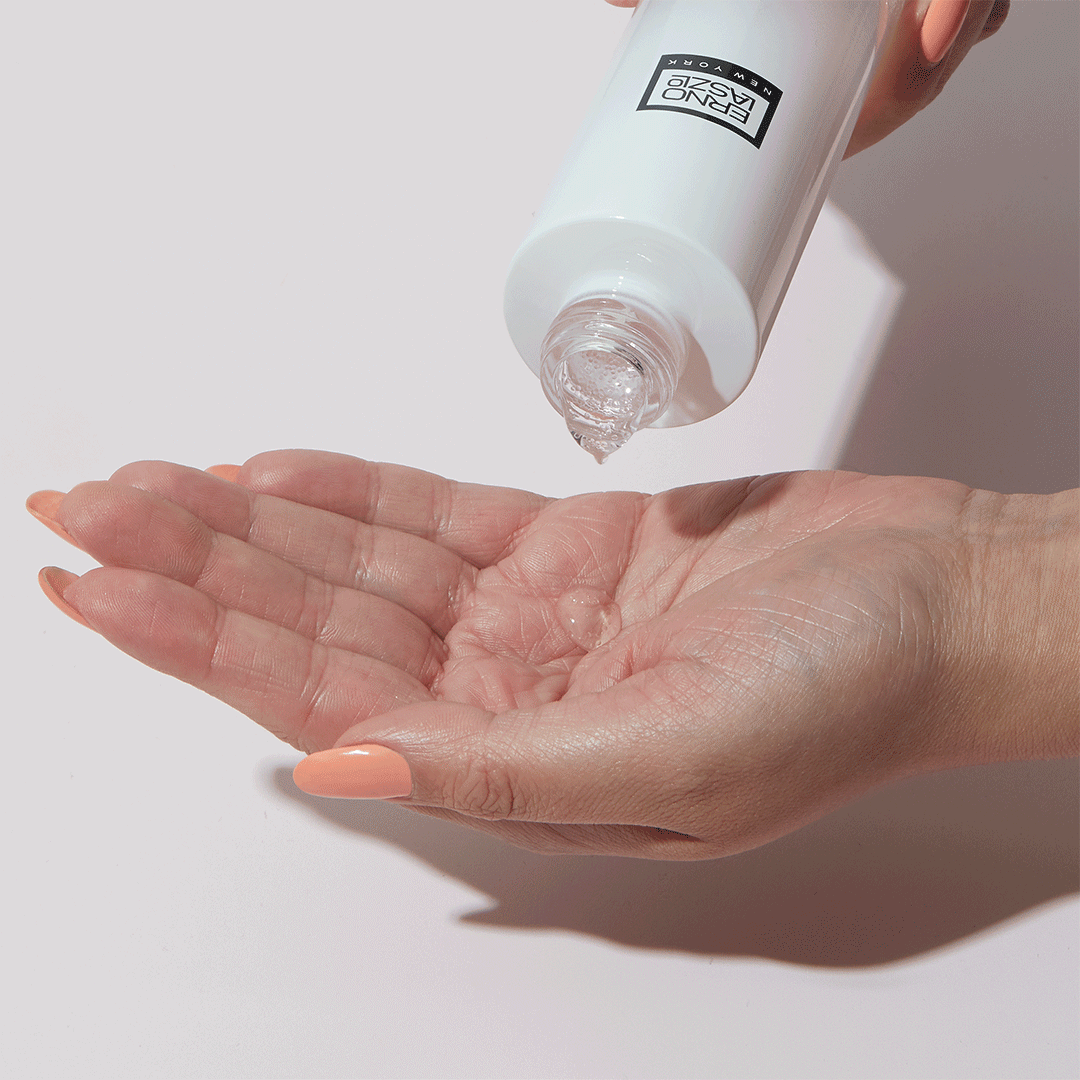 White squeeze skincare serum bottle dispensing clear gel onto open palm